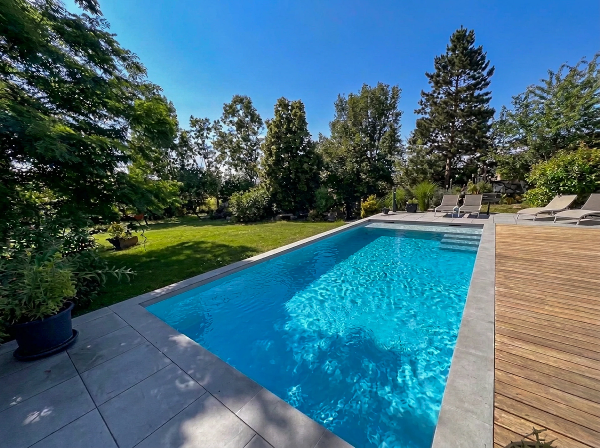 Piscine intérieure de spa illuminée en bleu électrique, avec cascade décorative en acier inoxydable brossé en forme d'arche circulaire
