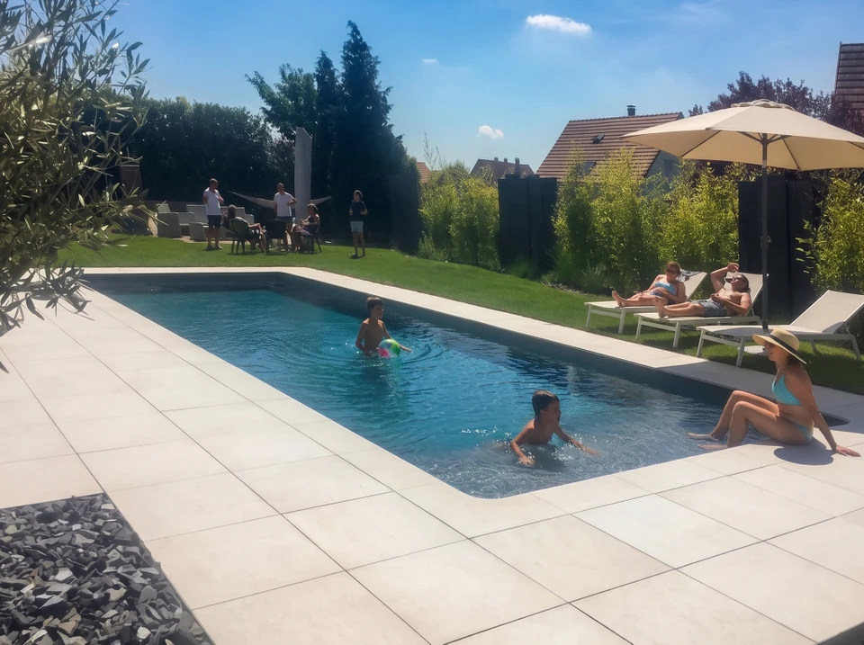 Piscine rectangulaire extérieure aux eaux turquoise cristallines, entourée d'un dallage en travertin beige
