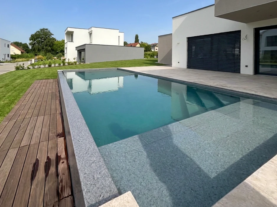Piscine rectangulaire extérieure aux eaux turquoise cristallines, entourée d'une plage en dalles de grès cérame grand format ton béton clair