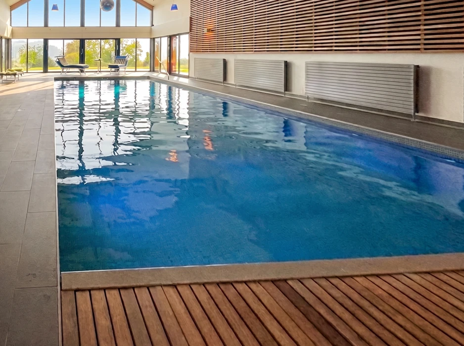 Piscine intérieure privée rectangulaire aux eaux bleu clair, entourée d'un dallage en pierre calcaire beige